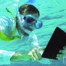 Homme sous l'eau avec masque et tuba consultant une tablette