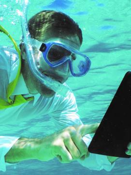 Homme sous l'eau avec masque et tuba consultant une tablette