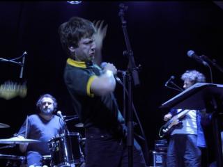Un chanteur s'exprime sur scène, entouré de musiciens