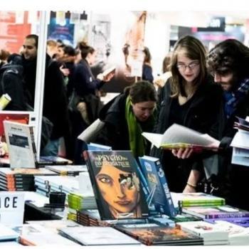 Des jeunes feuilletent des livres devant un stand