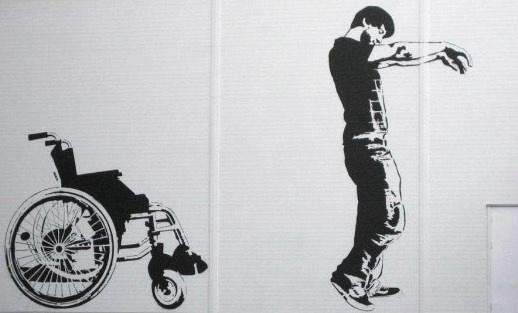 Fauteuil d'handicapé et homme debout devant le fauteuil. Dessin de couleur noir sur un mur au fond blanc
