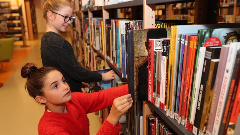 Collégiennes cherchant des livres sur un bibliothèque