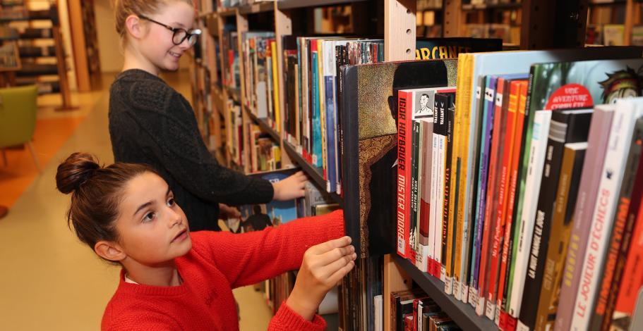 Collégiennes cherchant des livres sur un bibliothèque